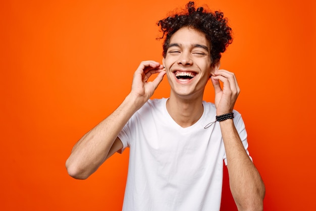 Leuke kerel met krullend haar witte t-shirt bijgesneden weergave oranje achtergrond