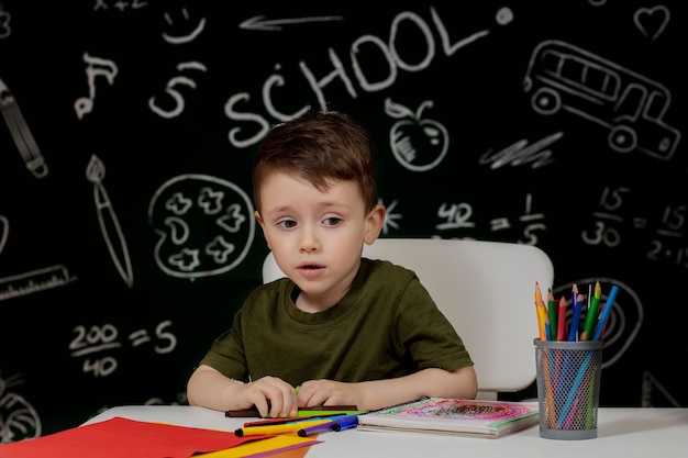 Leuke kindjongen die huiswerk doet Slimme jongen tekenen aan het bureau Schooljongen Basisschoolstudent tekenen op het werk Kind geniet van leren Thuisonderwijs Terug naar school Kleine jongen op school les