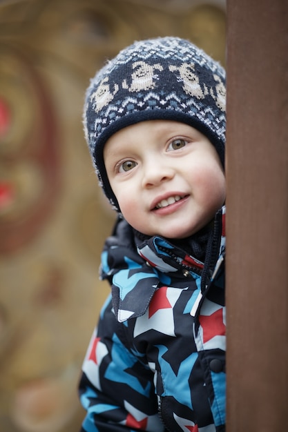 Leuke kleine jongen die rond een deur tuurt