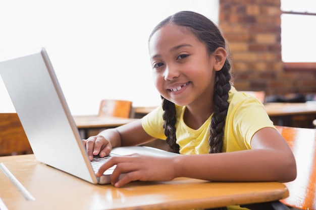 Leuke kleine leerling die laptop in klaslokaal bekijkt