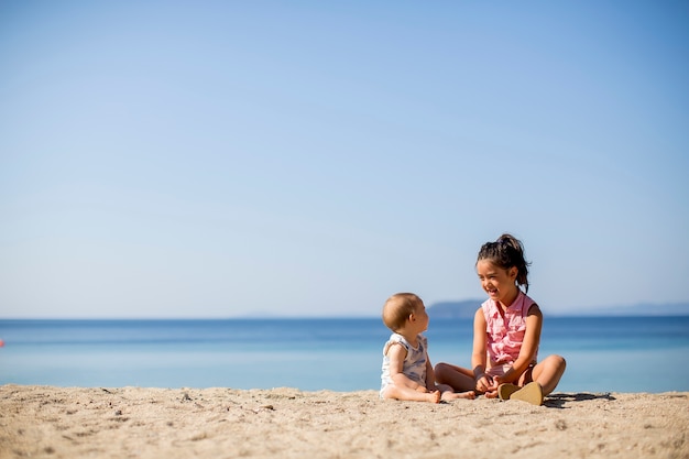 Leuke kleine zusters die op een strand zitten