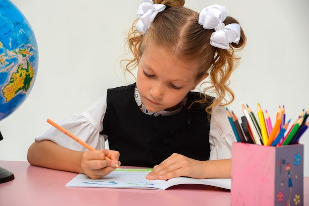 Leuke leerling die bij haar bureau op witte achtergrond werkt