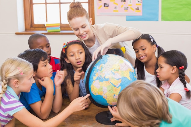 Leuke leerlingen en leraar in klas met globe