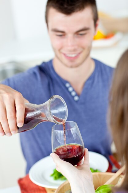 Leuke man die met zijn meisje thuis dineert die haar wijn dient