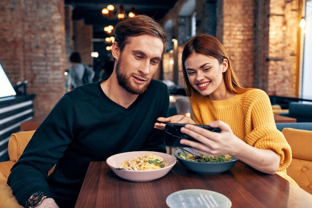 Leuke mannen en vrouwen in een restaurant met een telefoon in hun handen selfie