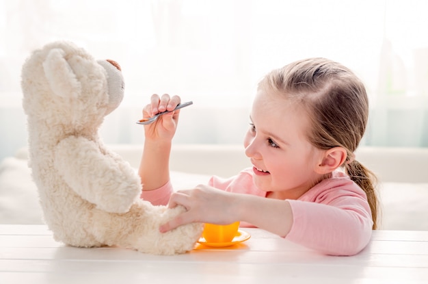 Leuke meisje voedende stuk speelgoed teddybeer