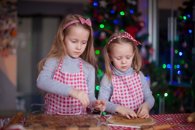 Leuke meisjes die peperkoekkoekjes voorbereiden op kerstmis