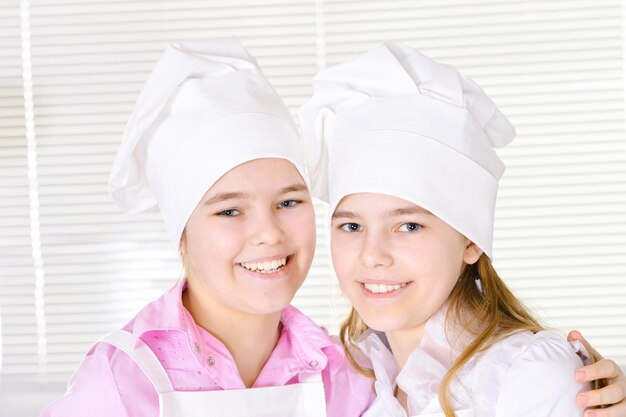 Leuke meisjes in koksmutsen en schorten in de keuken thuis