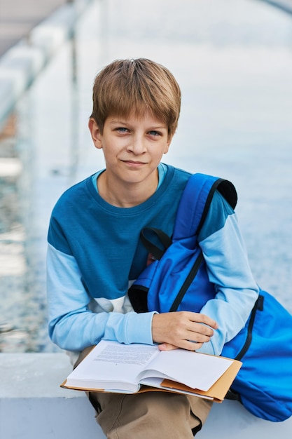 Leuke middelbare schoolleerling die met open boek camera bekijkt