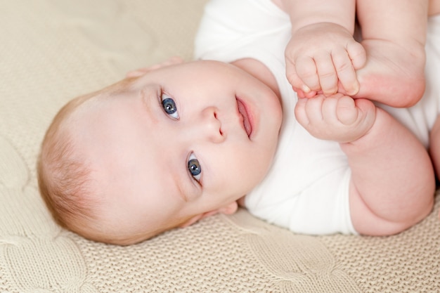 Leuke mooie baby met grote ogen ligt op het bed