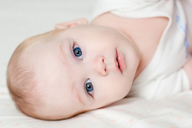 Leuke mooie baby met grote ogen ligt op het bed