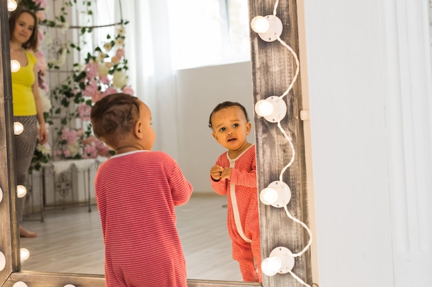 Leuke nieuwsgierige baby bestudeert dingen in de kamer.