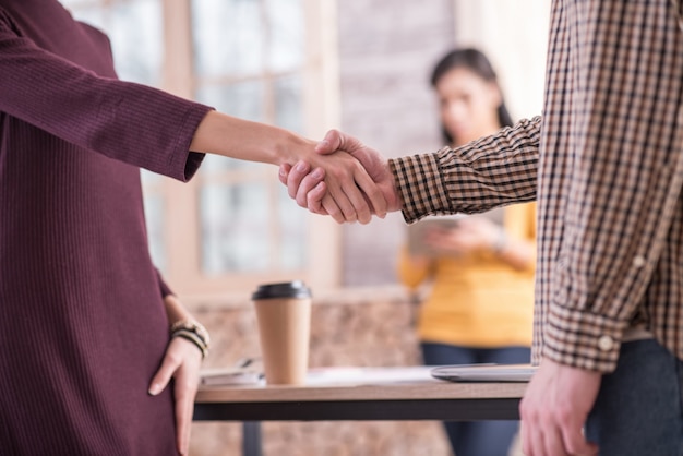 Leuke ontmoeting. Vriendelijke handdruk tussen positieve aardige vrienden terwijl ze elkaar ontmoeten