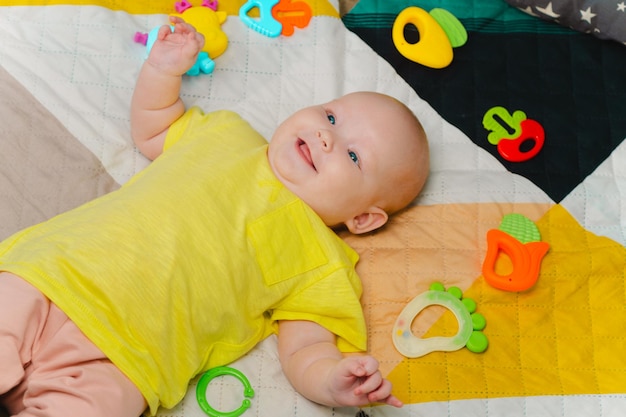 Leuke pasgeboren baby omringd door kleurrijke speelgoed ligt thuis op het bed