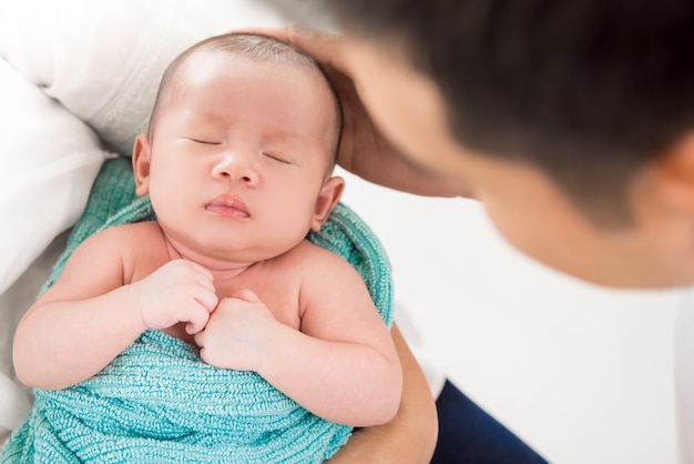 Leuke pasgeboren slaapbaby in de wapens van jonge Aziatische ouder