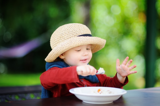 Leuke peuterjongen die rijstgraangewas in openlucht eet. Gezond voedsel voor kleine kinderen