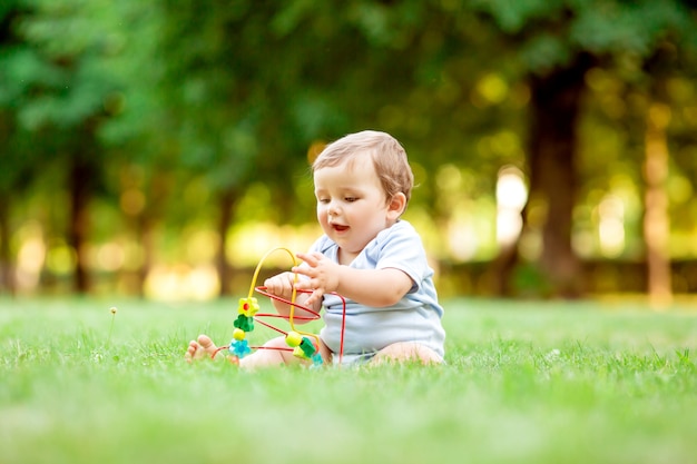 Leuke peuterjongen in blauwe bodysuitzitting op het gras