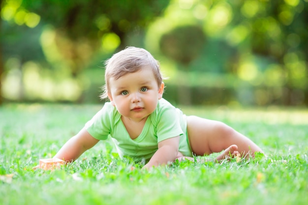 Leuke peuterjongen in groene bodysuitzitting op het gras