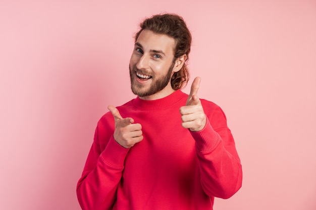 Leuke, positieve, glimlachende man toont een pistool met zijn vingers.