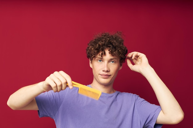 Leuke roodharige man in paarse t-shirts met een kam geïsoleerde achtergrond