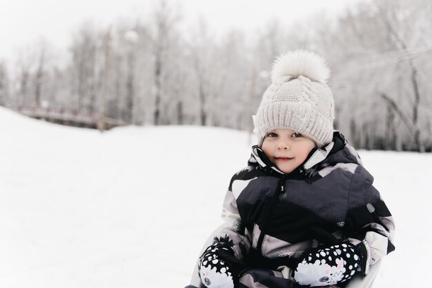 Leuke schattige jongen in een slee in de sneeuw actieve levensstijl winter familie