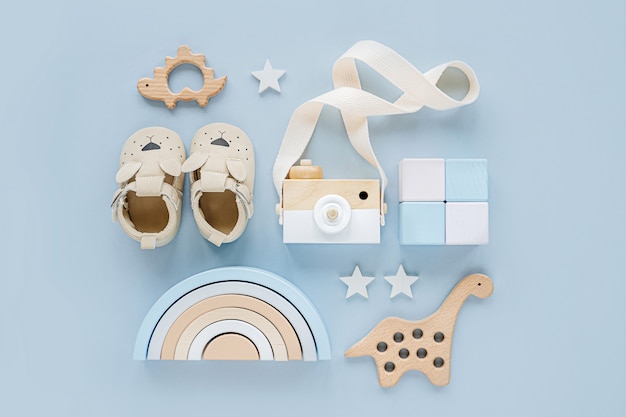 Leuke schoenen, bijtring, houten speelgoed en regenboog. set babyspullen en accessoires voor jongen op lichtblauwe achtergrond. babydouche-concept. mode pasgeboren. platliggend, bovenaanzicht