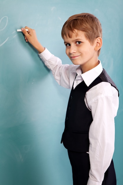 Leuke schooljongen die op een schoolbord schrijft