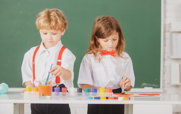 Leuke schoolvrienden kinderen tekenen en schilderen op school vriendelijke jongen een meisje grappige leerlingen tekenen vriend