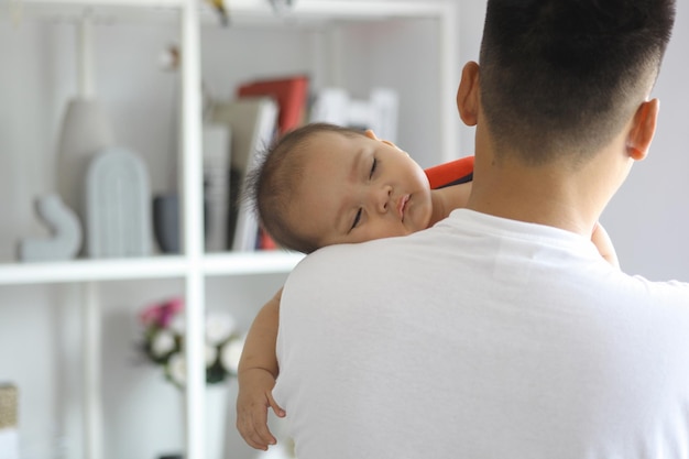 Leuke slaperige pasgeboren baby over zijn vaders schouders vaderschap en liefdevolle zorg concept