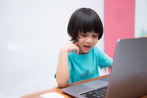 Leuke slimme Aziatische jongen gebruikt zijn laptop graag om thuis alleen online te studeren Online leerconceptZelfstudie