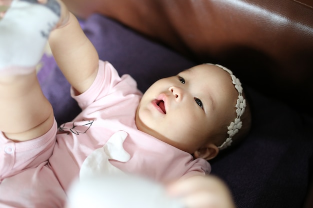 Leuke slimme Aziatische pasgeboren babyslaap met teddy konijnstuk speelgoed op roze zacht bed thuis.