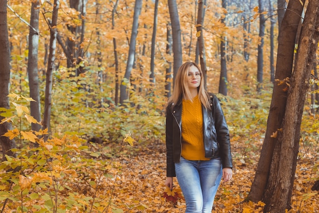 Leuke smiley vrouw met herfstbladeren in herfst park. Seizoens-, lifestyle- en vrijetijdsconcept.