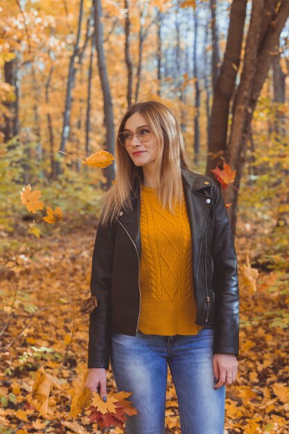 Leuke smiley vrouw met herfstbladeren in herfst park. Seizoens-, lifestyle- en vrijetijdsconcept.