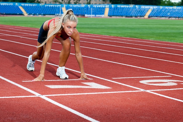 Leuke sportieve vrouw die zich voorbereidt om bij de startlijn te rennen