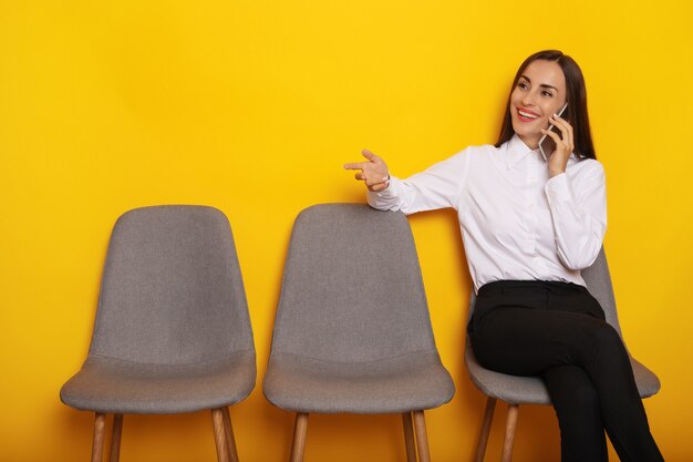 Leuke, stijlvolle, moderne brunette vrouw zit op de stoellijn op de afspraak voor een sollicitatiegesprek