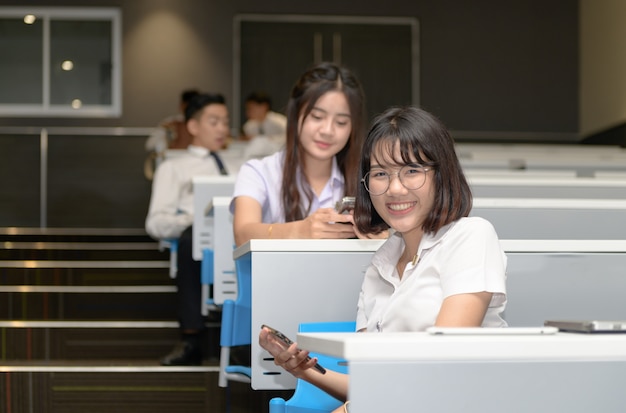 Leuke student spelen mobiele telefoon in de klas