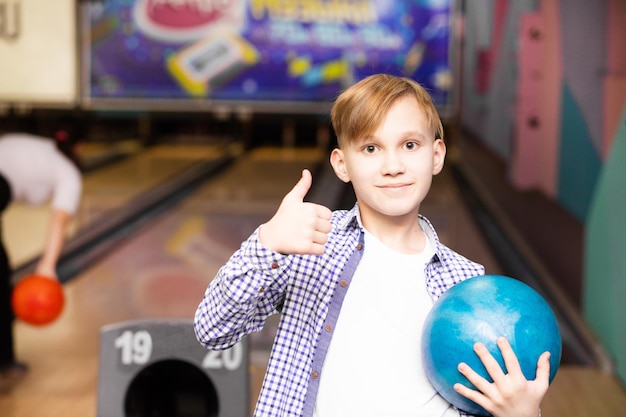 Foto leuke tiener met een bal in de bowlingclub.