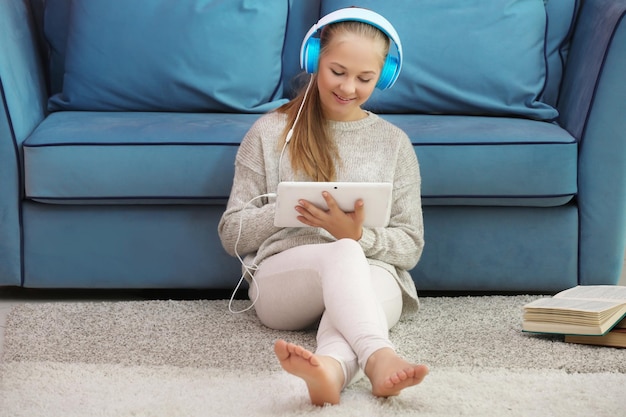 Leuke tiener met tablet zittend op de vloer in de kamer