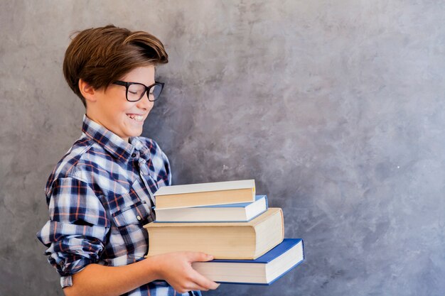 Leuke tienerschooljongen die boeken houdt