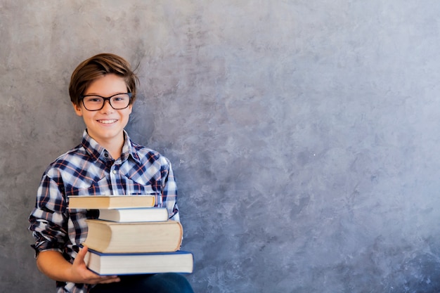 Leuke tienerschooljongen die boeken houdt