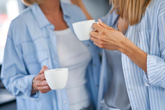 Leuke twee volwassen meisjes in de keuken met koffie