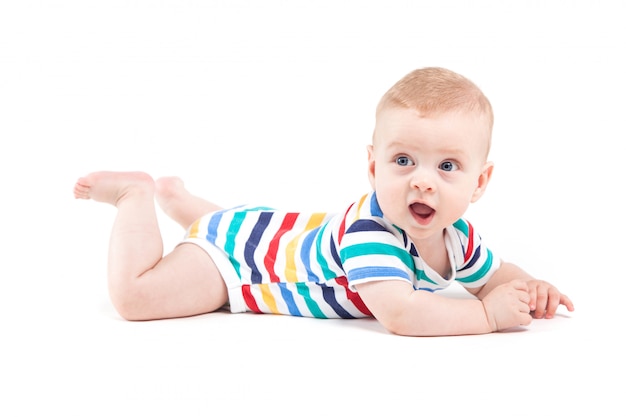 Leuke verbaasde kleine jongen in kleurrijk overhemd ligt op buik