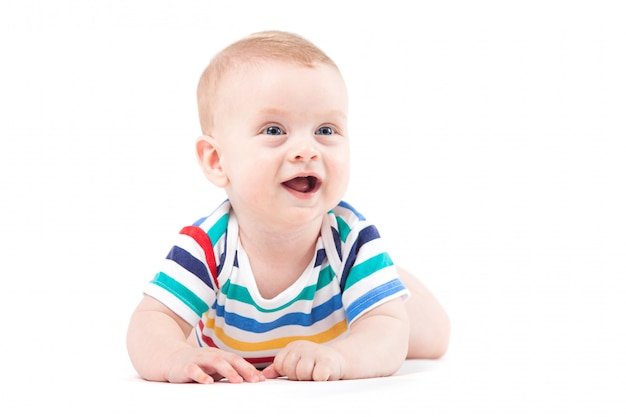 Leuke verbaasde kleine jongen in kleurrijk overhemd ligt op buik