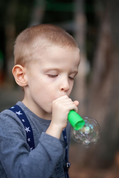 Leuke voorschoolse blanke kindjongen die zeepbellen blaast in het park