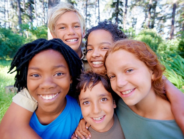 Leuke vrienden en frisse lucht Een close-up van het beeld van een groep kinderen die naar de camera glimlachen terwijl ze in het bos staan