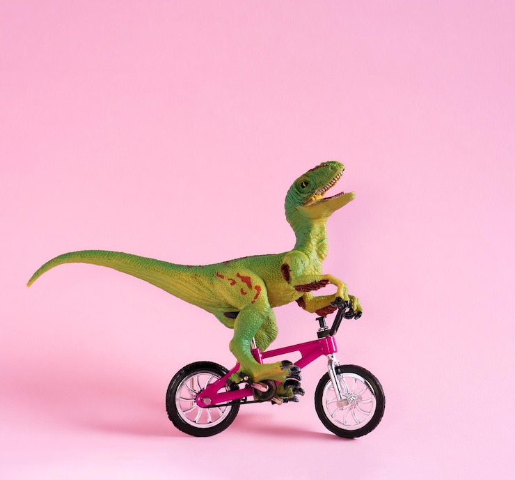 Foto leuke vrolijke dinosaurus speelgoed fiets op pastel roze achtergrond leuke milieuvriendelijke transportconcept kaart