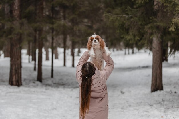 Leuke vrouw die met hond speelt in het winterparkbos