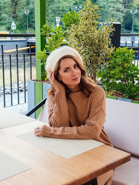 Leuke vrouw die wacht op het menu op het straatterras van het café Het model draagt een beige trui