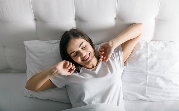 Leuke vrouw die wakker wordt bij haar witte bed