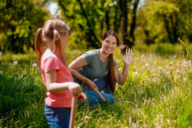 Leuke vrouw en een blond meisje die tijd doorbrengen in de tuin en aan het planten zijn